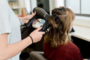 A person blow-drying a woman’s hair